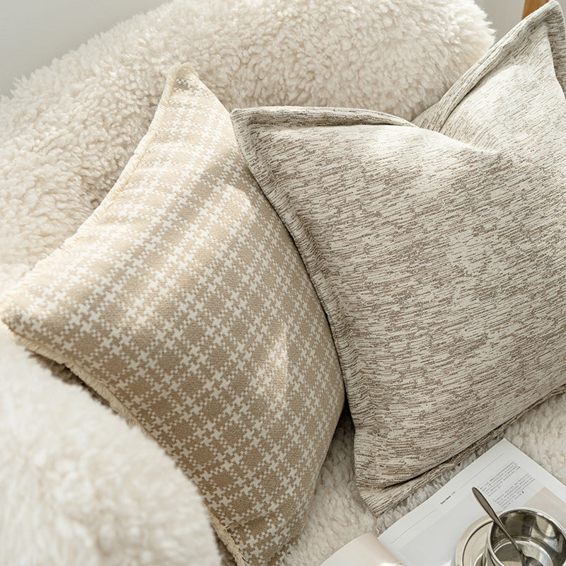 Close-up of textured pillows on a sofa with a magazine and bowl in the background.