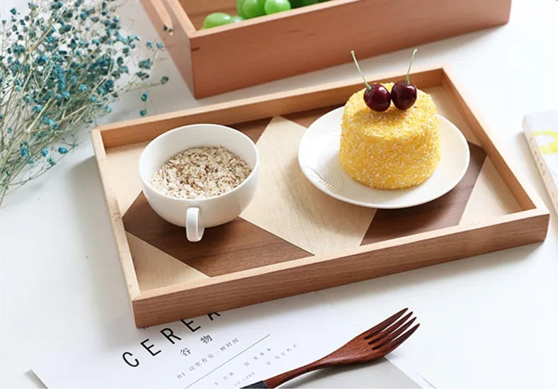 Wooden tray with a cup of cereal, a small cake, and a fork on a white surface.