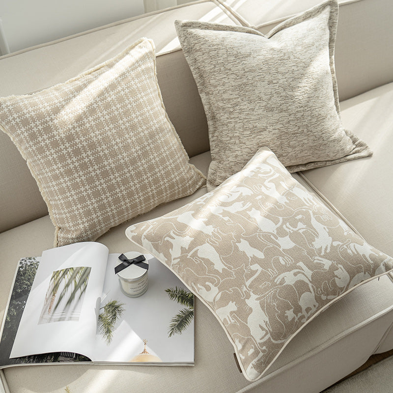 Decorative pillows on a sofa with a magazine and small bowl.