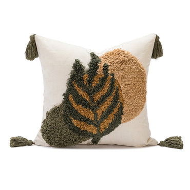 A square throw pillow with a cream-colored base featuring a raised, textured abstract design of a leaf in olive green and tan, with matching olive green tassels on the corners, set against a plain white background.